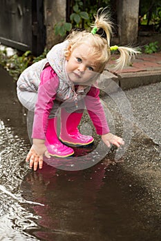 A little girl is standing in a puddle, autumn rains