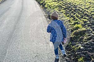 Little girl standing on the road in the countryside and looking at the horizon