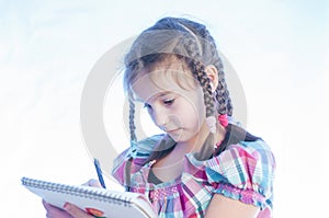 little girl stands and does writes in a notebook