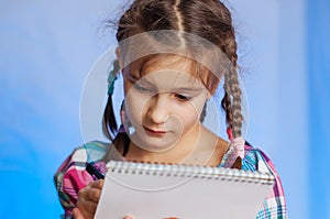 little girl stands and does writes in a notebook