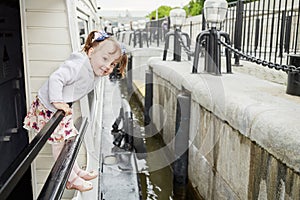 Little girl stands holding on railing at pleasure photo