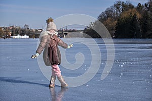 Little girl stands in the middle of a frozen river
