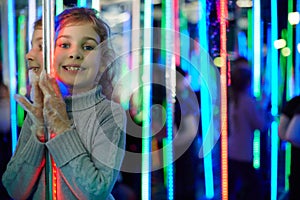 Little girl stands in mirror labyrinth