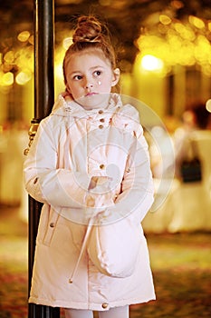 Little girl stands pensively fumbling in handbag