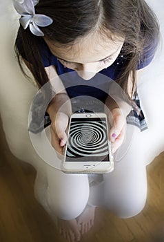 Little girl staring at hypnosis spiral on her cell phone