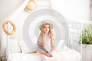 Little girl in a straw hat and dress on a background of a bright white bedroom with a rustic interior. Childhood concept. Provence