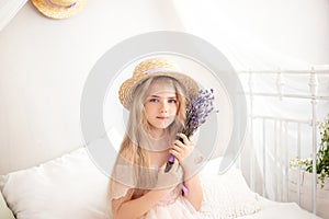 Little girl in a straw hat and dress on a background of a bright white bedroom with a rustic interior. Childhood concept. Provence