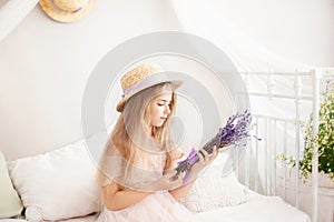 Little girl in a straw hat and dress on a background of a bright white bedroom with a rustic interior. Childhood concept. Provence