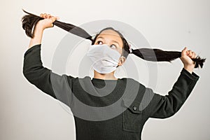 Little girl stretches her pigtails desperately and wildly. Little girl locked up at home during quarantine coronavirus. Concept