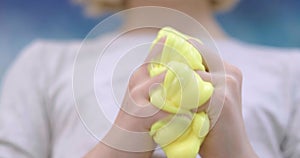 Little girl stretches yellow slime to the sides, hands close up stretching vibrant yellow slime, creative and fun