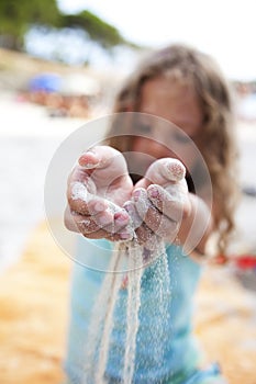 Little girl strew sand throw her fingers