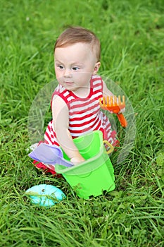 Little girl in a striped dress plays with a pail