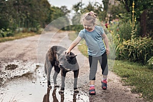 Little girl stroking a big black stray dog in the street