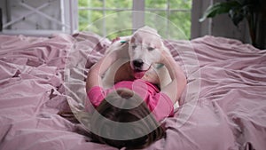 Little girl stroking her puppy in bedroom