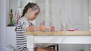 Little girl studying alone making notes, children elementary education concept. Cute smart primary school child girl learning writ