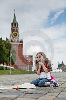 The little girl in stylish dress sitting near the Kremlin