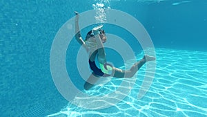 Little girl submerged in blue transparent water of swimming pool