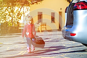 Little girl with suitcases travel by car, family tourism