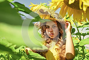little girl in sunflower field. yellow flower of sunflower. happy childhood. beautiful girl wear straw summer hat in