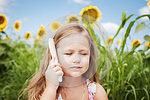 Little girl and sunflowers in a summer sunny day. Caring for your hair.