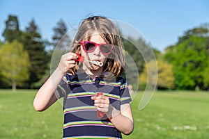Little girl in sunglasses in summer inflates soap bubbles