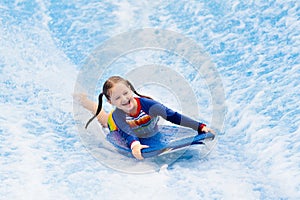 Little girl surfing in beach wave simulator