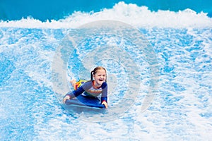 Little girl surfing in beach wave simulator