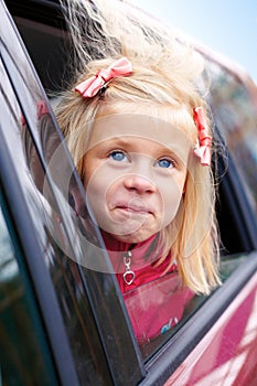 Little girl surprise stares out of the car