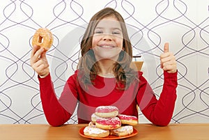 Little girl with sweet donuts and thumb up