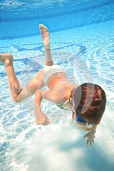 Little girl in swimming goggles swimming underwater