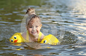 Little girl swimming in lake outdoors. Closeup