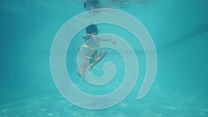 A little girl swimming and playing a snake toy underwater.