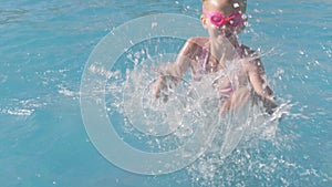 Little girl swimming in swimming pool, child having fun, splashing water, jumping. Summer travel family hotel vacation