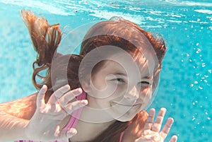 The little girl swimming underwater and smiling