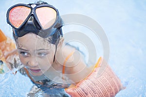 Little girl swims and plays in the outdoor pool