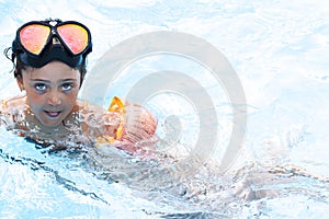 Little girl swims and plays in the outdoor pool
