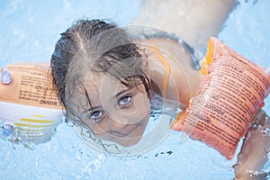 Little girl swims and plays in the outdoor pool