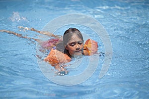 Little girl swims and plays in the outdoor pool