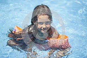 Little girl swims and plays in the outdoor pool