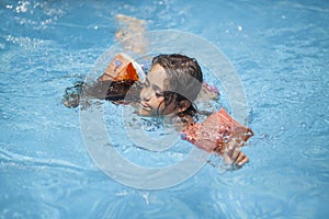 Little girl swims and plays in the outdoor pool