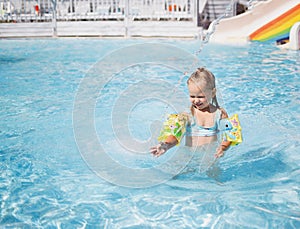 Little girl swims in the pool in the outdoor water park