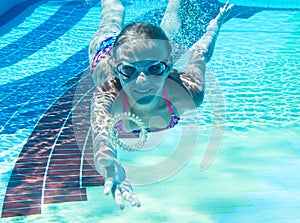 Little girl swims in the pool underwater