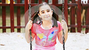 Little girl on swing smiling at camera