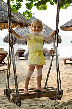 Little girl swinging with the beach in the background