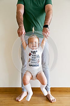 Little girl swinging on daddy& x27;s arms in the room