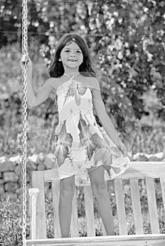 Little girl swinging on a summer sunny day. Child dreaming on swing. Child swinging on playground on sunny summer day in