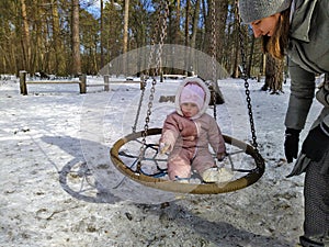 Little girl swinging on swing in snowy forest