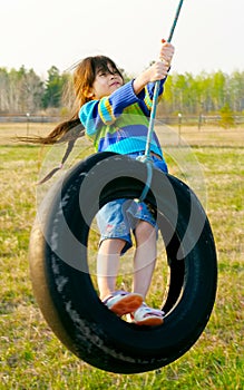 Little girl swinging on tire swing