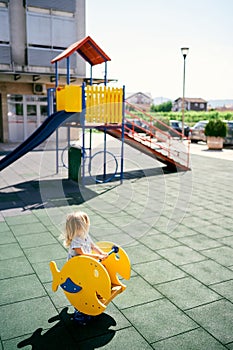 Little girl swings on a swing-balancer in the playground