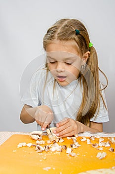 The little girl at table with diligence knife cutting mushrooms